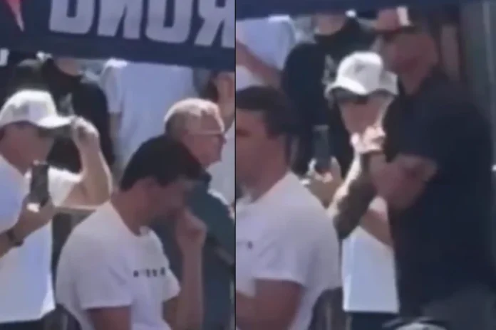 2 men standing behind Charlie Kirk look like they gave hand signals